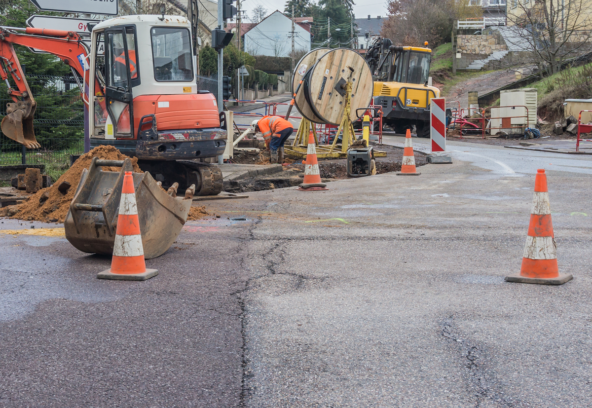 Construction work disrupts city traffic to dig trenches and lay fiber cable.